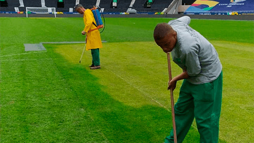 Aplicação manual de corante em campo de futebol